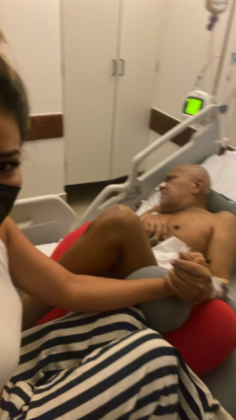 Mulher segurando a mão de um homem acamado no leito de hospital.