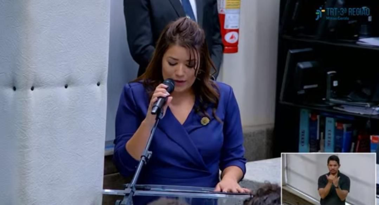 Mulher segurando um microfone enquanto faz um discurso.