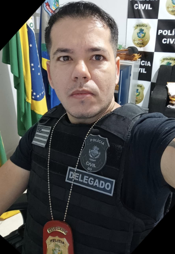 Selfie de um homem com distintivo e colete escrito "delegado", ao fundo, um painel escrito "polícia civil".